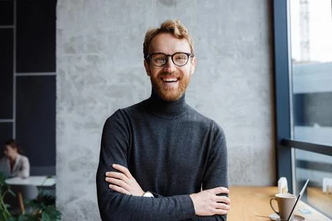 A young red-haired guy, a programmer or an entrepreneur in glasses, in a stylish Stock Photos