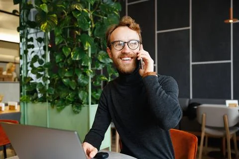 A young red-haired guy, a programmer or entrepreneur in glasses, sits in a Stock Photos