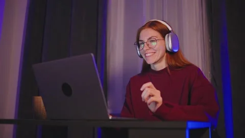 A young red-haired programmer woman in eyeglasses and headphones is answered on Stock Footage 297552418