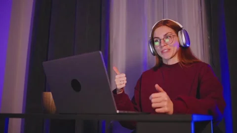 A young red-haired programmer woman in eyeglasses and headphones is answered on Stock Footage 297552558