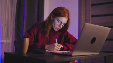 A young red-haired programmer woman is deeply focused while working late at Stock Footage 297553149