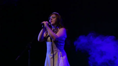 A young red-haired singer sings on stage with professional lighting and puffs of Stock Footage 106404869