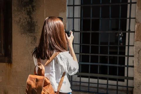 A young red-haired tourist with a backpack takes photographs of the narrow Stock Photos
