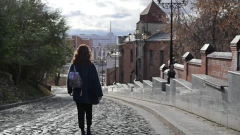 Young red-haired woman in a blue coat and walks against the backdrop of the old Stock-Footage 159574191