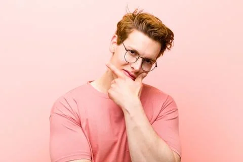 Young red head man looking serious, thoughtful and distrustful, with one arm  Stock-Fotos