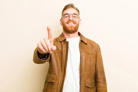 Young red head man smiling proudly and confidently making number one pose tri Stock Photos