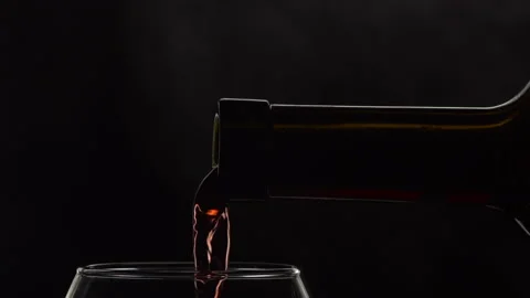 Young red or rose wine pouring from bottle into glass. Smoke Stock Footage 143078583