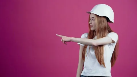The young redhead with the engineer's helmet points with her index finger to one Video stock 153698497