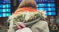 Young redhead girl waiting for train in crowded area, looking at timetable board HD Footage