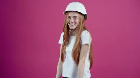 The young redhead with the white helmet of an engineer smiles optimistically and Stock Footage 153977649