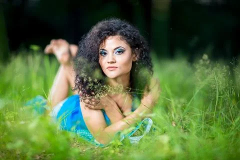 Young relaxing female lying on her stomach in the grass Stock Photos