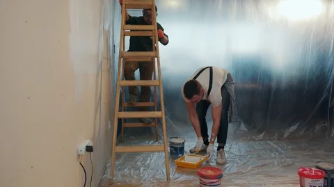 Young repairers working hard, one of the repairers stands on the wooden ladder Stock Footage 87382897