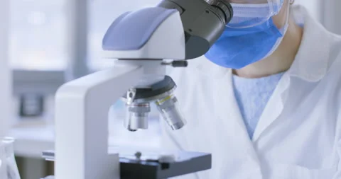 Young researcher analyzing samples under a microscope Stock Footage 211348928