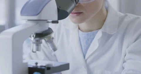 Young researcher analyzing samples under a microscope Stock Footage 211351056
