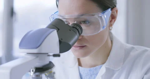 Young researcher analyzing samples under a microscope Stock Footage 211352317