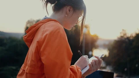A young, responsible student writes down new ideas for the project in her Stock Footage 160487077