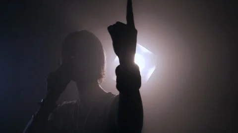 Young rockstar singer headbanging on stage with backlight Stock Footage 107783850