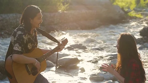 Young romantic couple enjoying time outdoors. Man is singing a love serenade Stock Footage 76009682