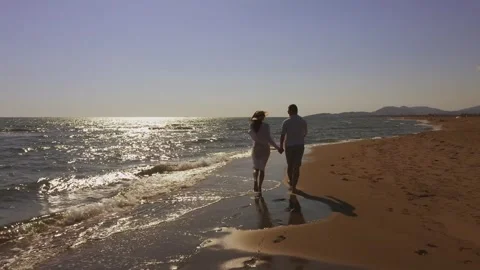 Young romantic couple holding hands and walking together along peaceful sea.. Stock Footage 337419191