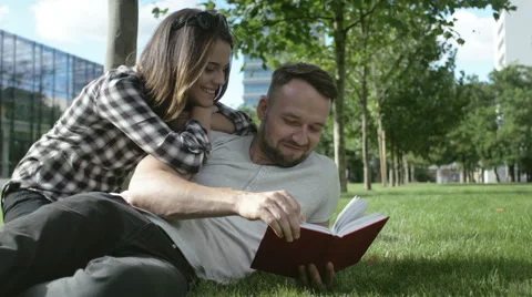 Young romantic couple spending time in park and reading a book. Stockbeeldmateriaal 55078375
