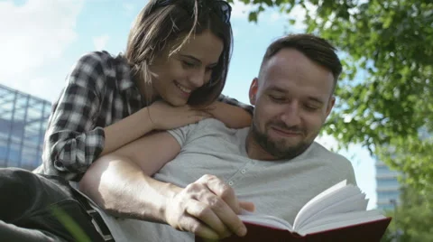 Young romantic couple spending time in park and reading book. Stock Footage 55162882