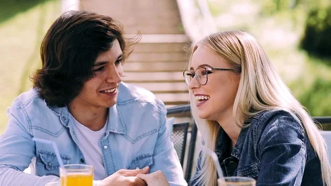 Young romantic couple spending time together sitting in cafe's garden Stock Footage 89825223