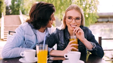 Young romantic couple spending time together sitting in cafe's garden Stock Footage 89825538