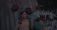 Young Romantic Multi-Ethnic Hipster Couple Flirting Lying Down On Jetty Stock Footage