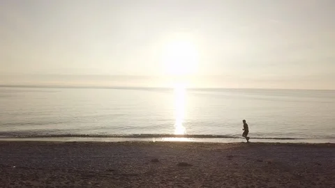 Young runner man training on beautiful sunset at beach. Drone tracking Stock Footage 122304168