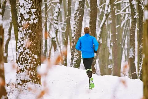 Young runner in winter jogging in forest Stock Photos