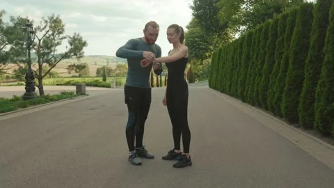 Young running athlete man and woman looking at smartwatch talking fitness Stock Footage 138634331