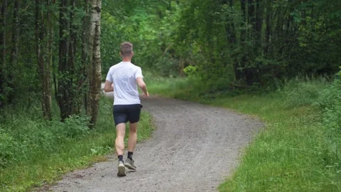 Young running athlete man jogging in the forest path Stock Footage 134172610