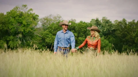A young rural couple walking through high grass on their Texas ranch. Stock Footage 140553931