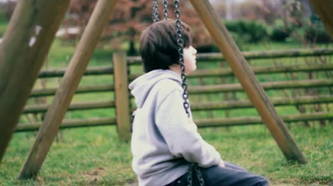 Young, sad, lonely boy on a swing, dolly shot Stock Footage