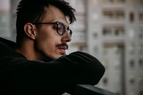 Young sad man looking down from a balcony Stock Photos