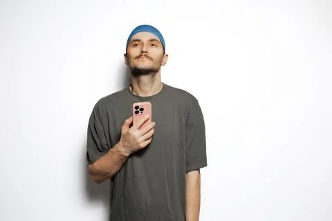 Young sad man using smartphone isolated on white background. Looking up. Stock Photos