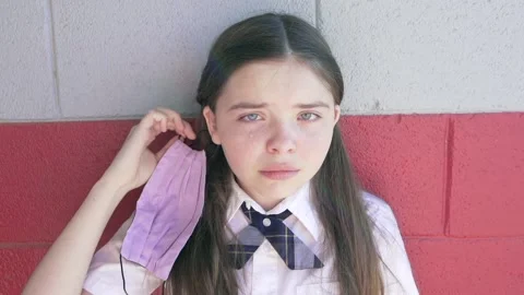 Young sad school pulls her mask off as a tear is seen. Video stock 168490261