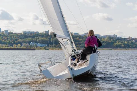 A young sailing instructor conducts a class with two female novices on a river Foto stock