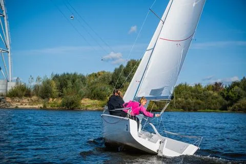 A young sailing instructor conducts a class with two female novices on a river Stock Photos