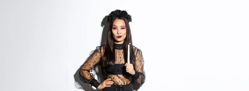 Young sassy witch practice magic with lit candle on halloween, wearing gothic Stock Photos