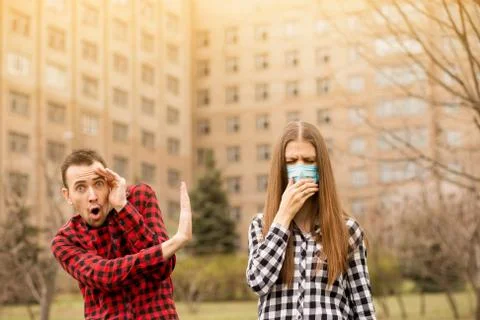 Young scared man afraid cough woman in medical mask outdoor. keep distance. Fotos de archivo