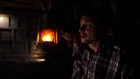 Young scared man in an old house illuminates the walkway with a kerosene lamp Stock Footage 137970676