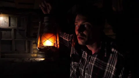 Young scared man in an old house illuminates the walkway with a kerosene lamp Stock Footage 138898526