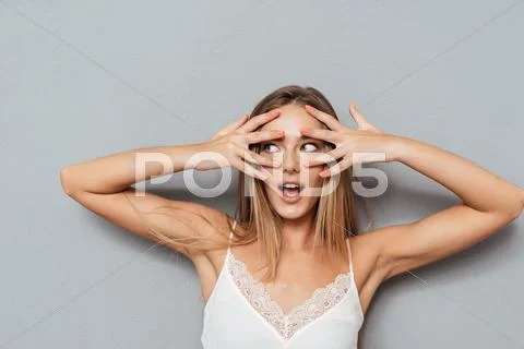Young scared woman looking away through fingers Stock Photos