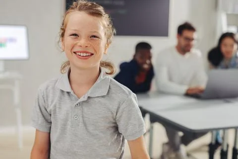 Young school boy smiling at the camera in a coding class, with his classmat.. Stock Photos