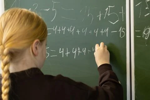 A young schoolchild writes complex math equations on a green classroom blac.. Stock Photos