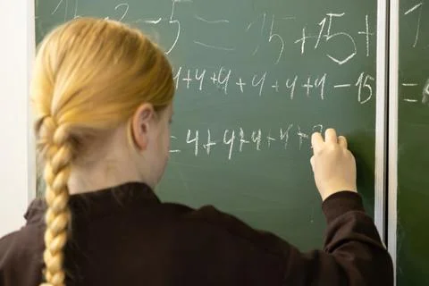 A young schoolchild writes complex math equations with white chalk on a gre.. Stock Photos
