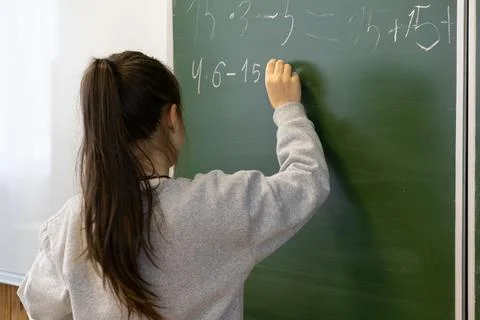 A young schoolchild writes complex mathematical equations on a green chalkb.. Stock Photos