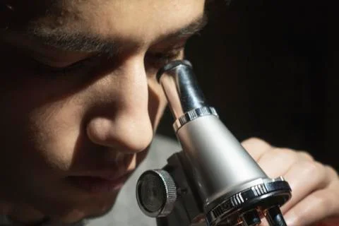 Young science student doing research looking through his microscope Stock Photos