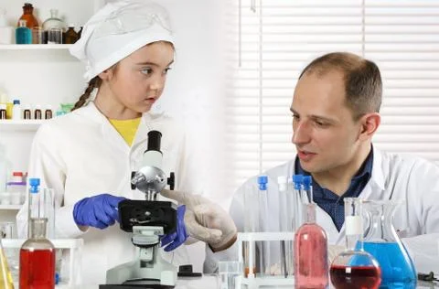 A young scientist explains how to use a microscope Stock-Fotos